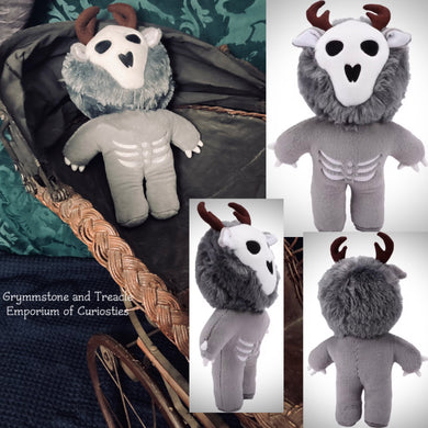 Gray plush toy with white face and black eyes, placed on a textured surface.