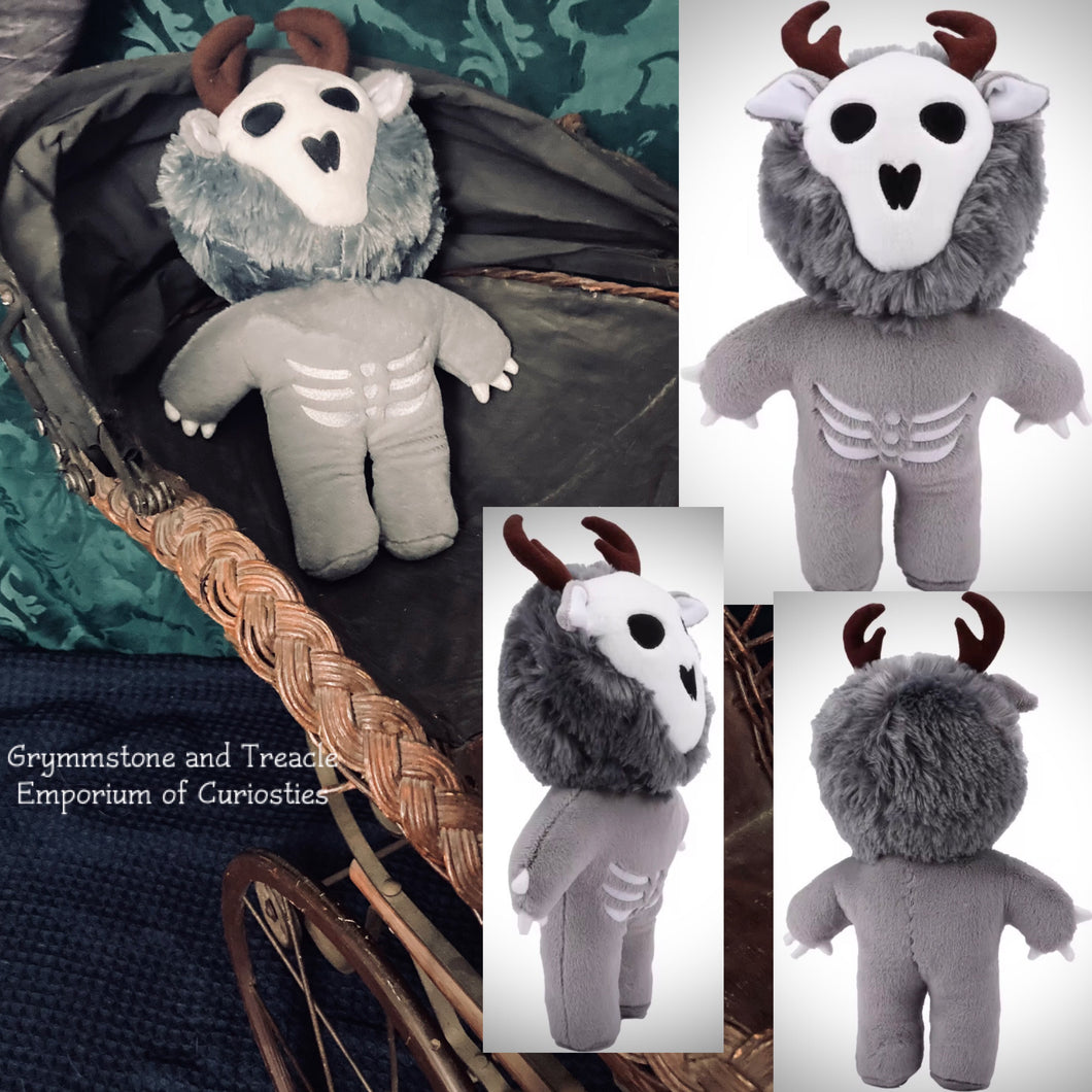 Gray plush toy with white face and black eyes, placed on a textured surface.