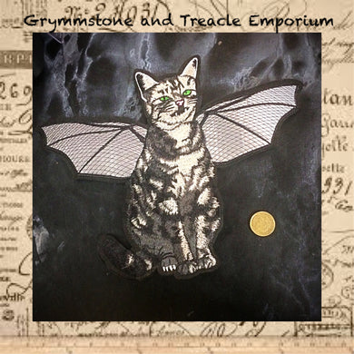 Embroidered iron on patch as a tortoiseshell cat with bat wings